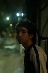 Santiago (2026) movie poster featuring a young man in a darkened cinema, projector light illuminating dust motes like stars, suggesting the return of a long-dead actor to the screen