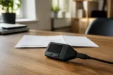 A Trezor hardware wallet sitting on a table with a blurred background showing a delivery receipt.