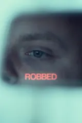 Poster for Robbed (2026) showing a shadowy figure clutching a bag of money on a rain‑slick street