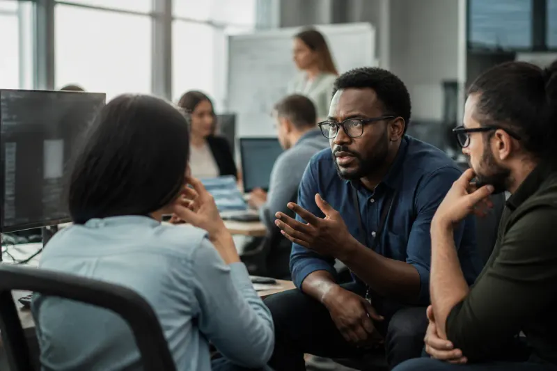 A group of cybersecurity experts discussing AI risks in a modern office.