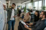 A busy office with multiple employees discussing cybersecurity strategies.