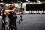 Compound archery event showcasing athletes aiming in a competitive indoor setting.