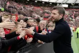 Michael Carrick smiling while walking on the pitch surrounded by Manchester United fans.