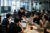 A group of security personnel exchanging information in a modern office workspace.